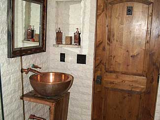 Bathroom with Copper Sink and Dark Wooden Door.